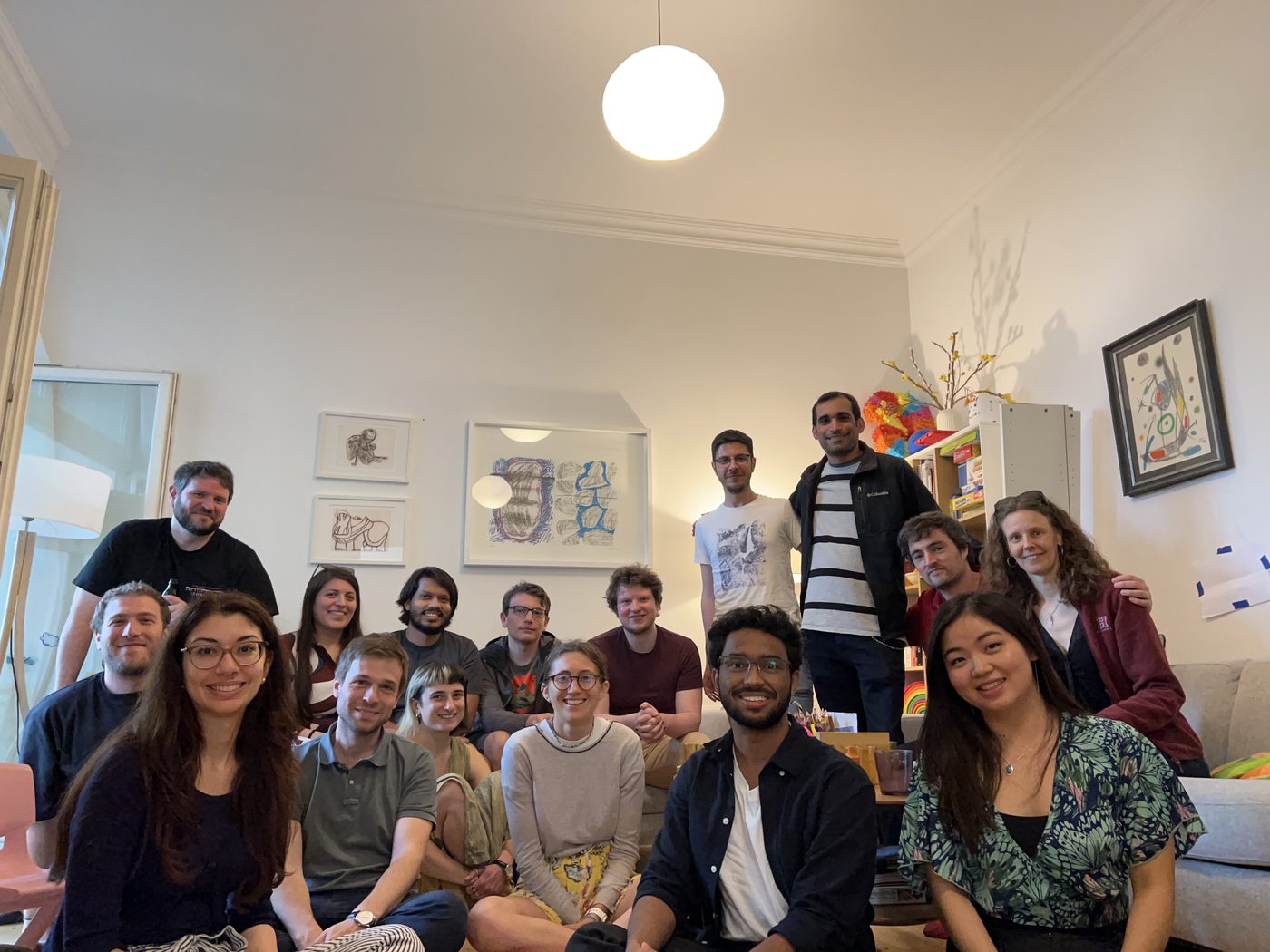A large group posing together in a living room, gathered on and around a sofa.